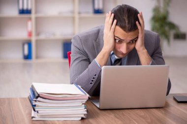 Ofisteki aşırı işten memnun olmayan genç bir erkek işçi.