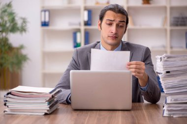 Ofisteki aşırı işten memnun olmayan genç bir erkek işçi.