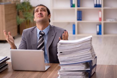 Ofisteki aşırı işten memnun olmayan genç bir erkek işçi.