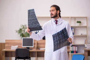 Genç erkek doktor radyoloji uzmanı ofiste oturuyor.