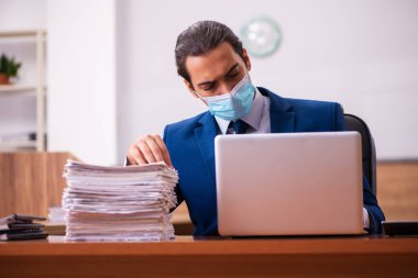 Ofiste maske takan genç bir erkek çalışan.