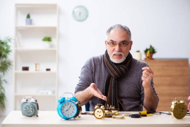 Atölyede çalışan yaşlı bir erkek saatçi.