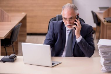 Ofisteki aşırı işten memnun olmayan yaşlı bir erkek işçi.