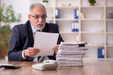 İş yerinde oturan yaşlı erkek çalışan.