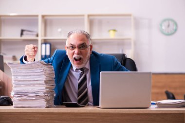 Ofisteki aşırı işten memnun olmayan yaşlı bir erkek işçi.