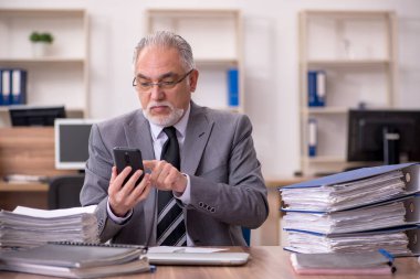 Ofisteki aşırı işten memnun olmayan yaşlı bir erkek işçi.