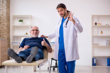 Yaşlı erkek hasta, genç erkek doktor masörünü ziyaret ediyor.