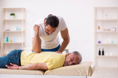 Yaşlı erkek hasta, genç erkek doktor masörünü ziyaret ediyor.