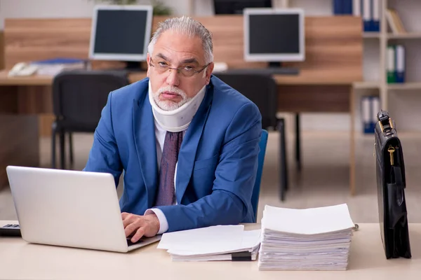 Old businessman employee after accident working in the office