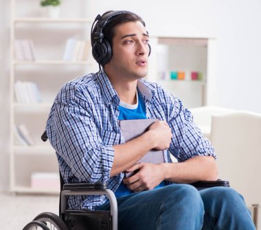 Tekerlekli sandalyede müzik dinleyen engelli adam.