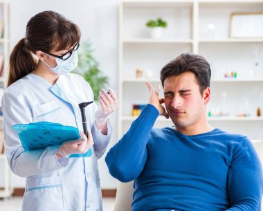 Doktor muayene sırasında hastaların kulaklarını kontrol ediyor.