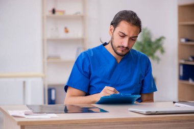 Klinikte çalışan genç erkek doktor.