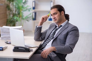 Ofisteki aşırı işten memnun olmayan genç bir erkek işçi.