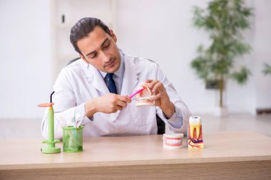 Genç erkek doktor stomatolojist klinikte çalışıyor.