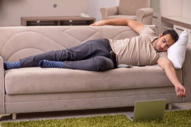 Evdeki kanepede yatan genç adam.