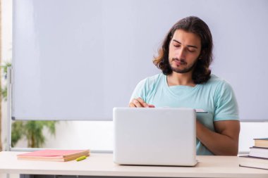 Genç erkek öğrenci tele-eğitim konsepti sınavlarına hazırlanıyor.