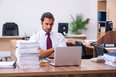 Ofisteki aşırı işten memnun olmayan genç bir erkek işçi.