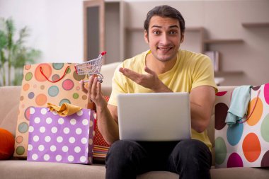 Evde bir sürü çantası olan genç bir adam var.