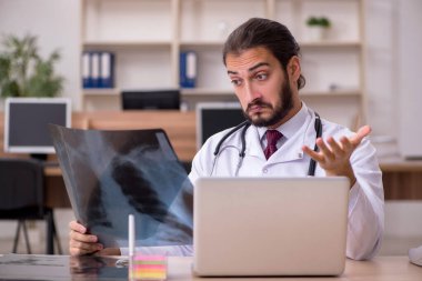 Genç erkek doktor radyoloji uzmanı ofiste oturuyor.