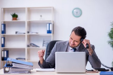 Ofisteki aşırı işten memnun olmayan genç bir erkek işçi.