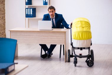 Genç erkek çalışan işyerinde çocuğa bakıyor.