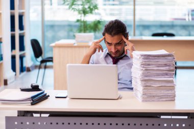Ofisteki aşırı işten memnun olmayan genç bir erkek işçi.