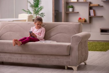 Evde kitap okuyan küçük bir kız.