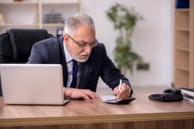 Yaşlı muhasebeci ofiste oturuyor.