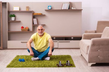 Yaşlı adam evde spor egzersizleri yapıyor.