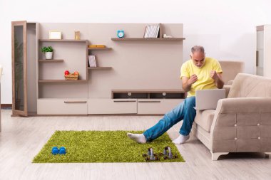 Yaşlı adam evde spor egzersizleri yapıyor.