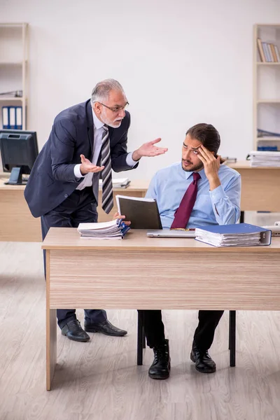 Oude mannelijke baas en jonge werknemer werken in het kantoor — Stockfoto
