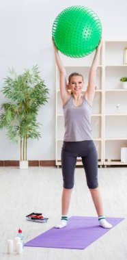 Spor salonunda denge topuyla egzersiz yapan genç bir kadın.