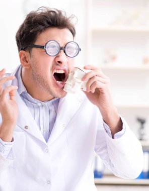 Deli doktor insan iskeletini inceliyor.