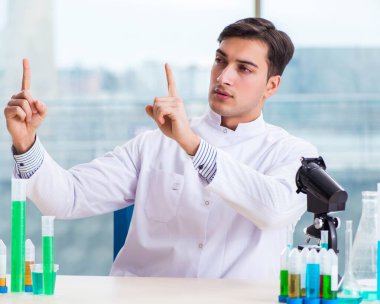 Laboratuvarda sanal düğmelere basan genç bir kimyager.