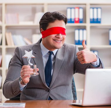 Ofiste masasında oturan gözü bağlı iş adamı.