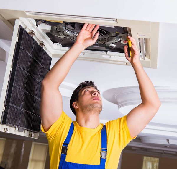 Repairman repairing ceiling air conditioning unit