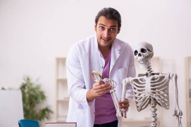 Sınıfta insan iskeleti üzerine çalışan genç bir erkek doktor.