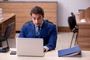 Genç adam işyerinde oturuyor.