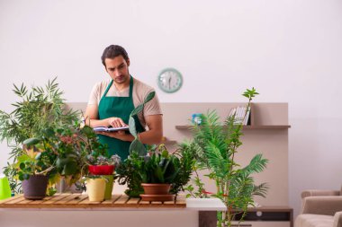 Evin içinde bitkileri olan genç bir erkek bahçıvan.