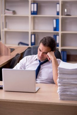 Ofisteki aşırı işten memnun olmayan genç bir erkek işçi.