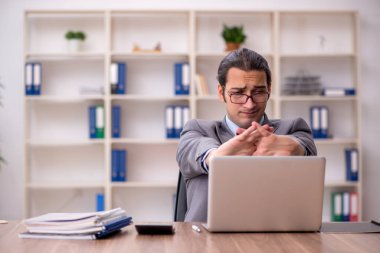 Genç erkek çalışan işyerinde oturuyor.