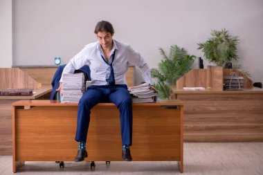 Ofisteki aşırı işten memnun olmayan genç bir erkek işçi.