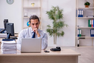 Genç erkek çalışan ofiste oturuyor.