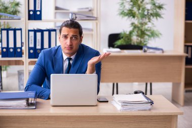 Genç yakışıklı çalışan ofiste oturuyor.