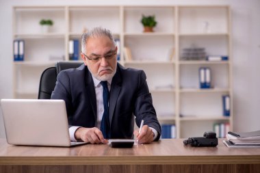 Yaşlı muhasebeci ofiste oturuyor.