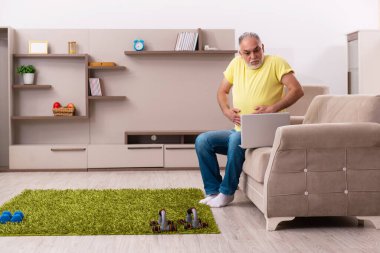 Yaşlı adam evde spor egzersizleri yapıyor.