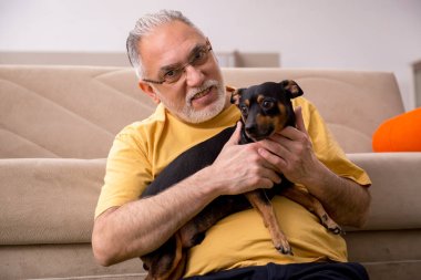 Evde köpeği olan yaşlı bir adam.