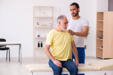 Yaşlı erkek hasta, genç erkek doktor masörünü ziyaret ediyor.