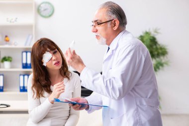 Genç kadın yaşlı erkek doktor göz doktorunu ziyaret ediyor.