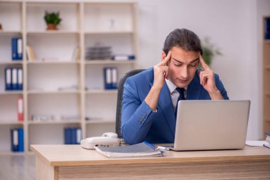 Genç erkek çalışan ofiste oturuyor.